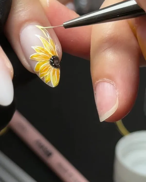Nude nails with a hand-painted yellow sunflower accent
