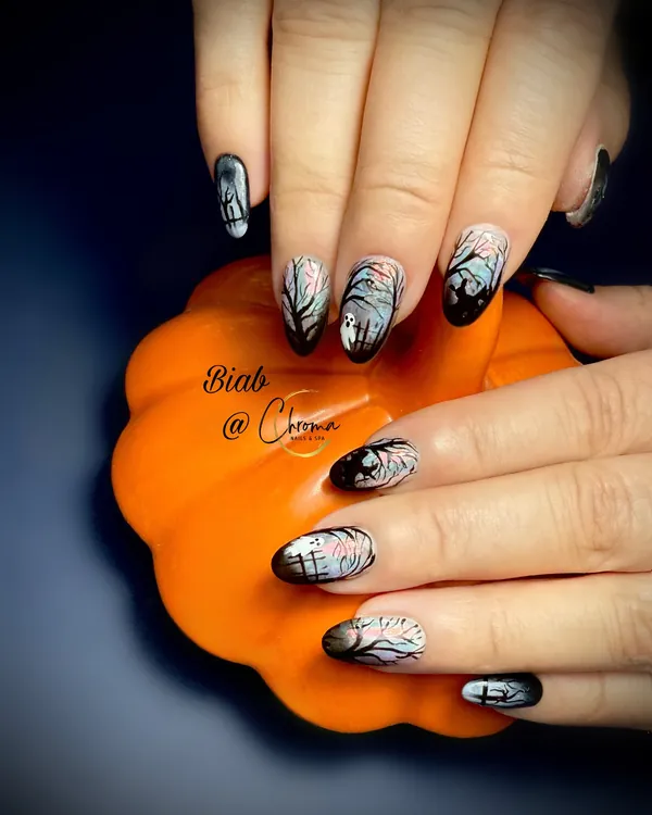 Almond nails with misty graveyard scenes, bare trees and tiny ghosts in black ombré