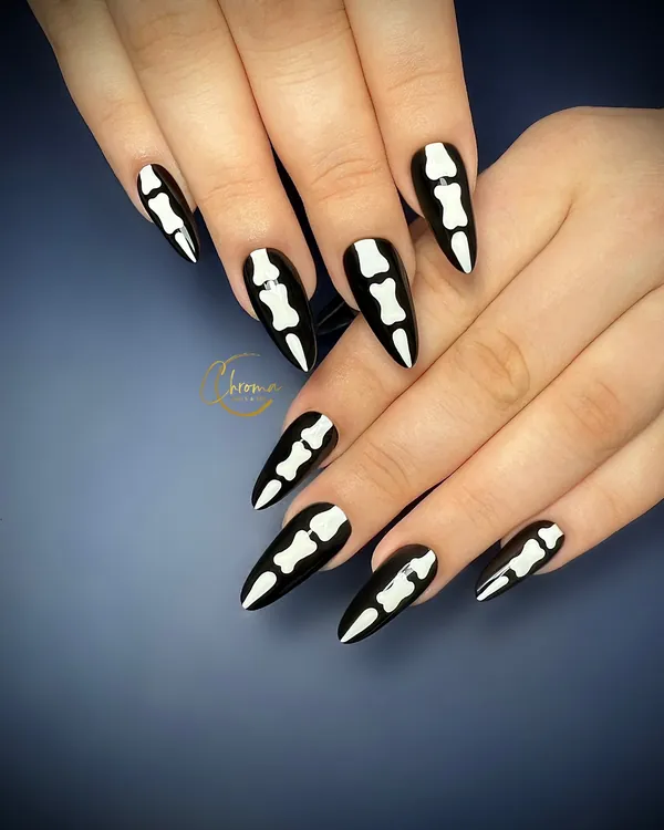Black stiletto nails painted with white skeleton finger bones
