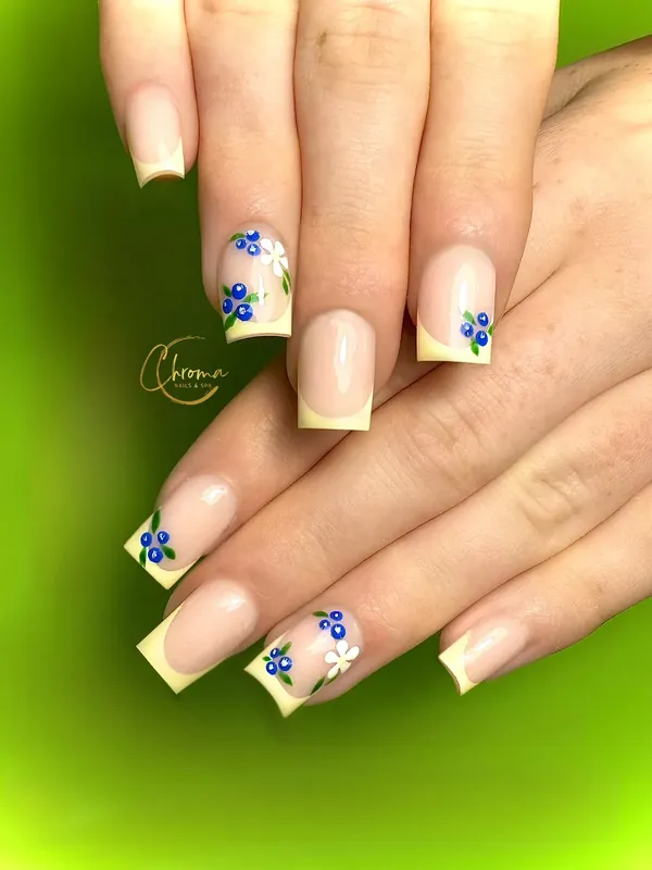 Soft yellow French tips with blueberries and tiny flowers