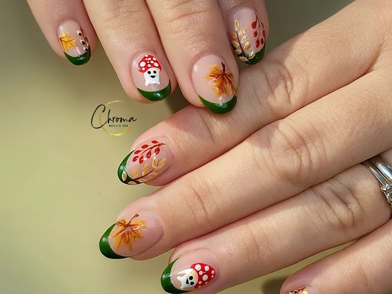 Green French tips with hand-painted autumn leaves and mushrooms at Chroma Nails & Spa